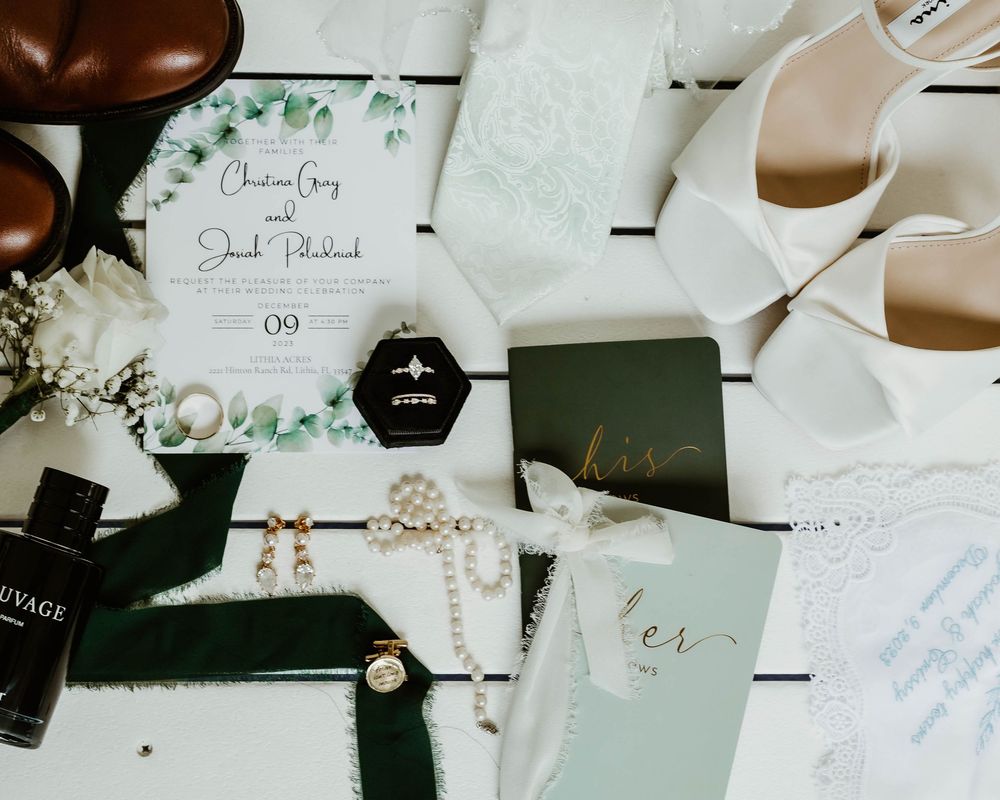 Wedding details including white stationery, eucalyptus leaves, and delicate floral elements arranged on a light surface.