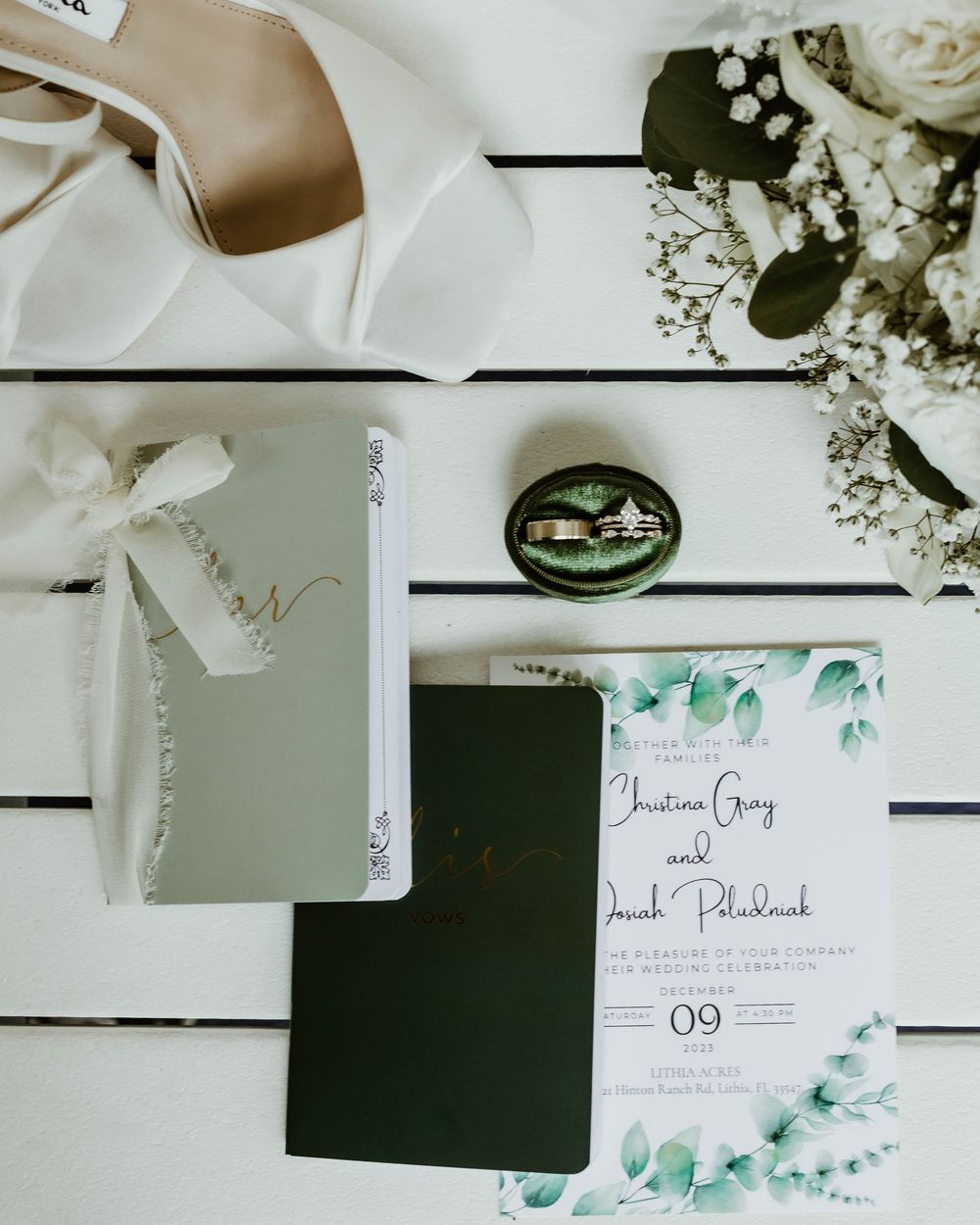 Wedding invitation suite with eucalyptus design displayed with floral elements on white background.