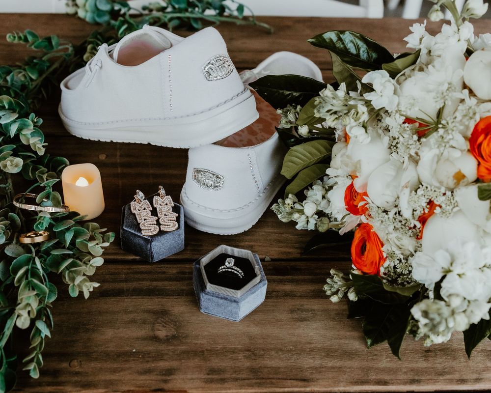 White sneakers and floral arrangements displayed on rustic wooden surface.