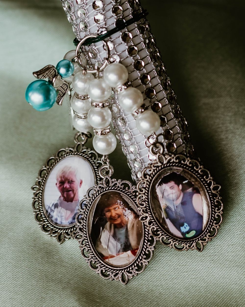 Vintage-style pendant necklace with ornate silver frames and pearls on a textured surface.