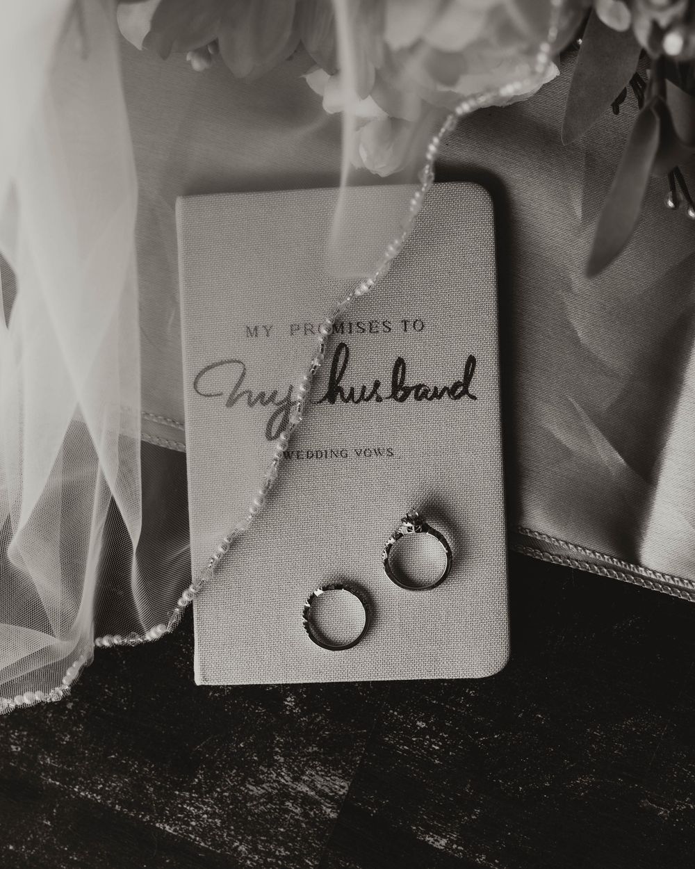 Wedding rings and vow book arranged artistically in black and white.