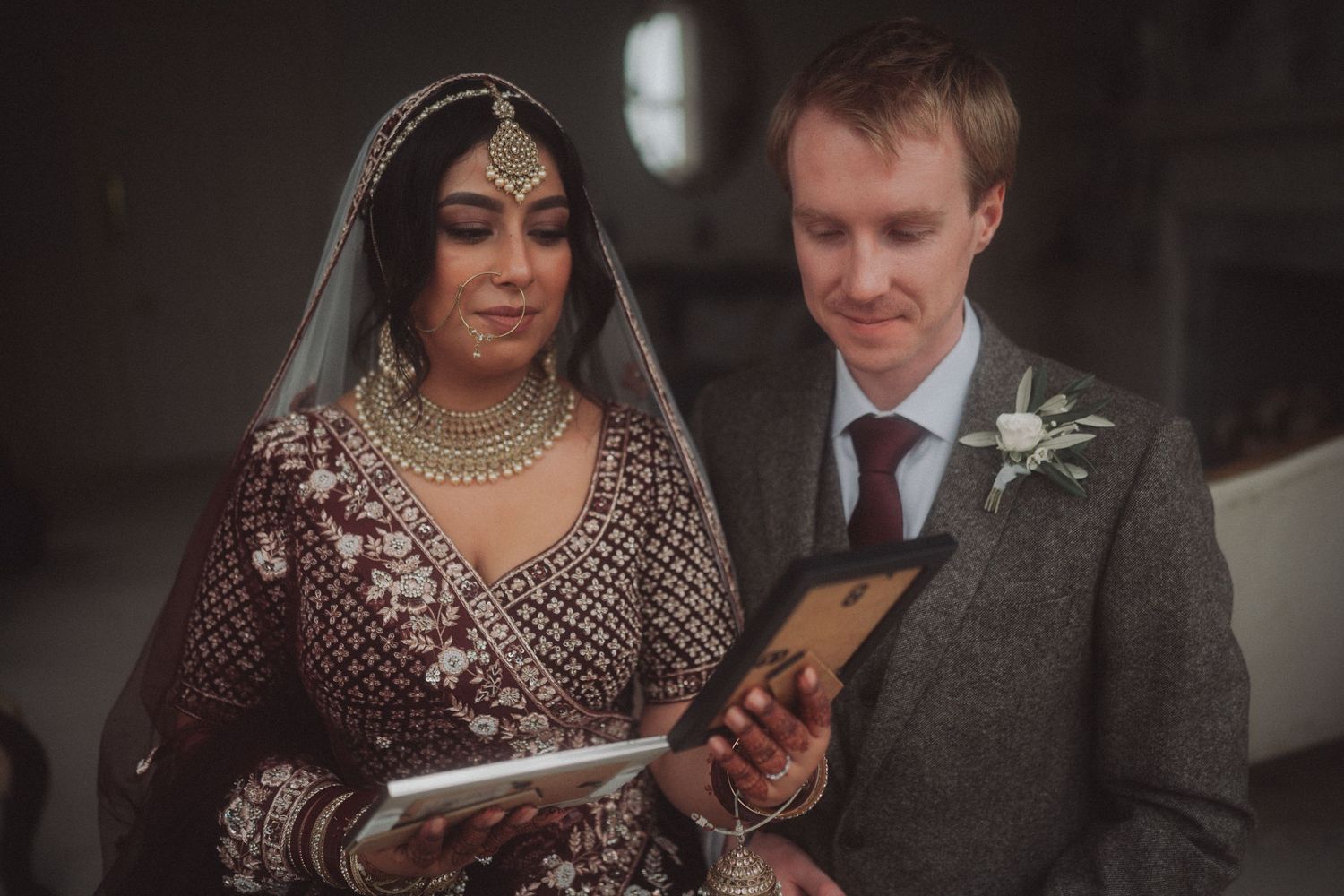 A couple in traditional wedding attire reviews documents together during their ceremony.
