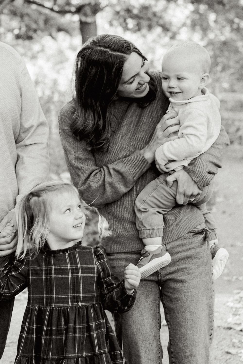 Black and white candid family moments captured during an outdoor photo session.