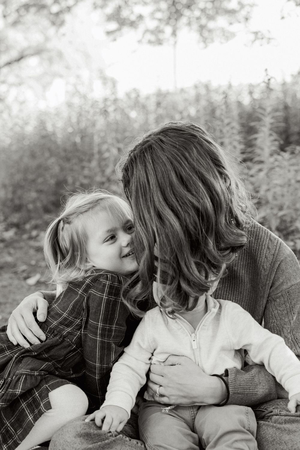 Black and white portrait of tender family moment outdoors in nature setting.