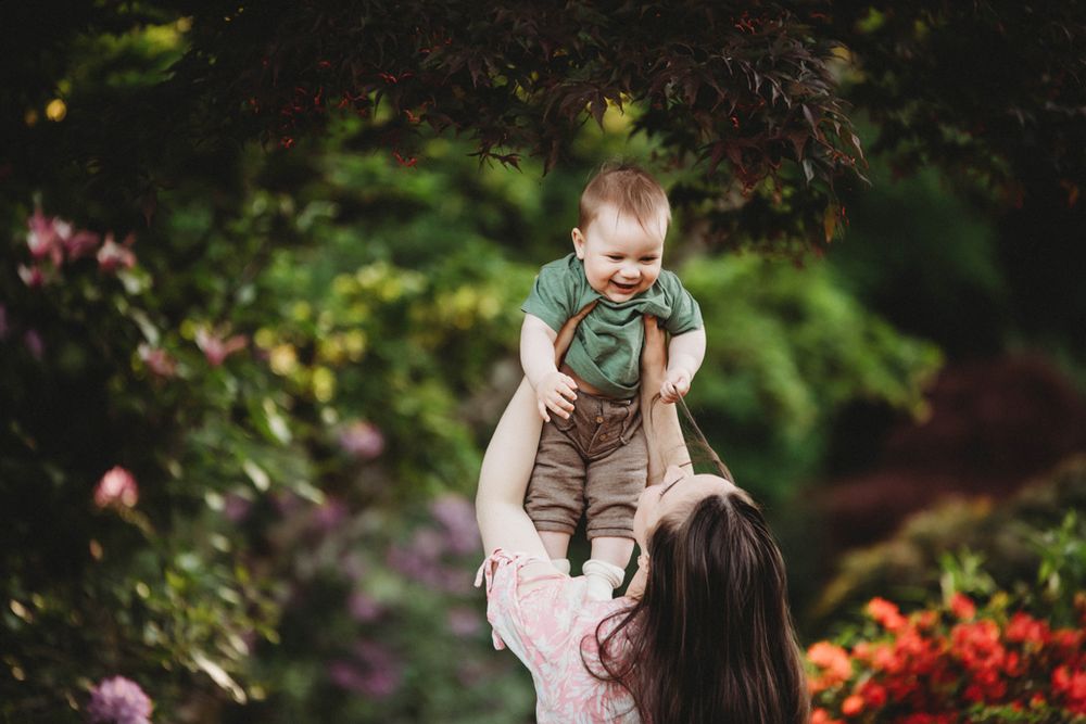 A joyful moment between parent and child playing together in a colorful garden setting with blooming flowers.