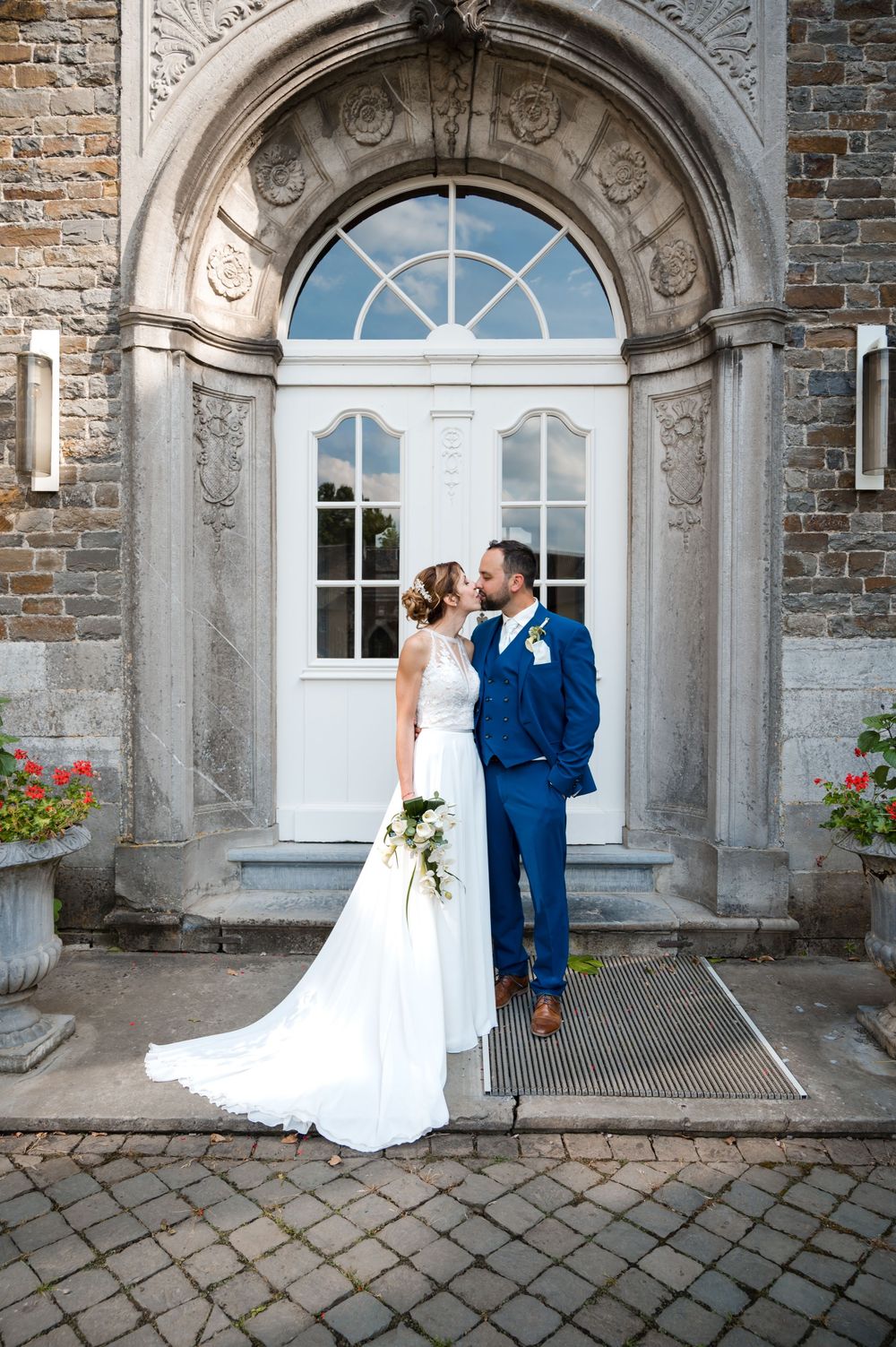 À Aubel, à l’abbaye de Val-Dieu, couple de mariés photographié s’embrassant devant une porte lors d’une séance photo de mariage