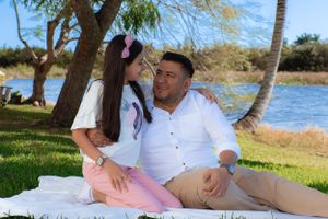 Father and daughter share a sweet moment sitting together on a blanket by the water.