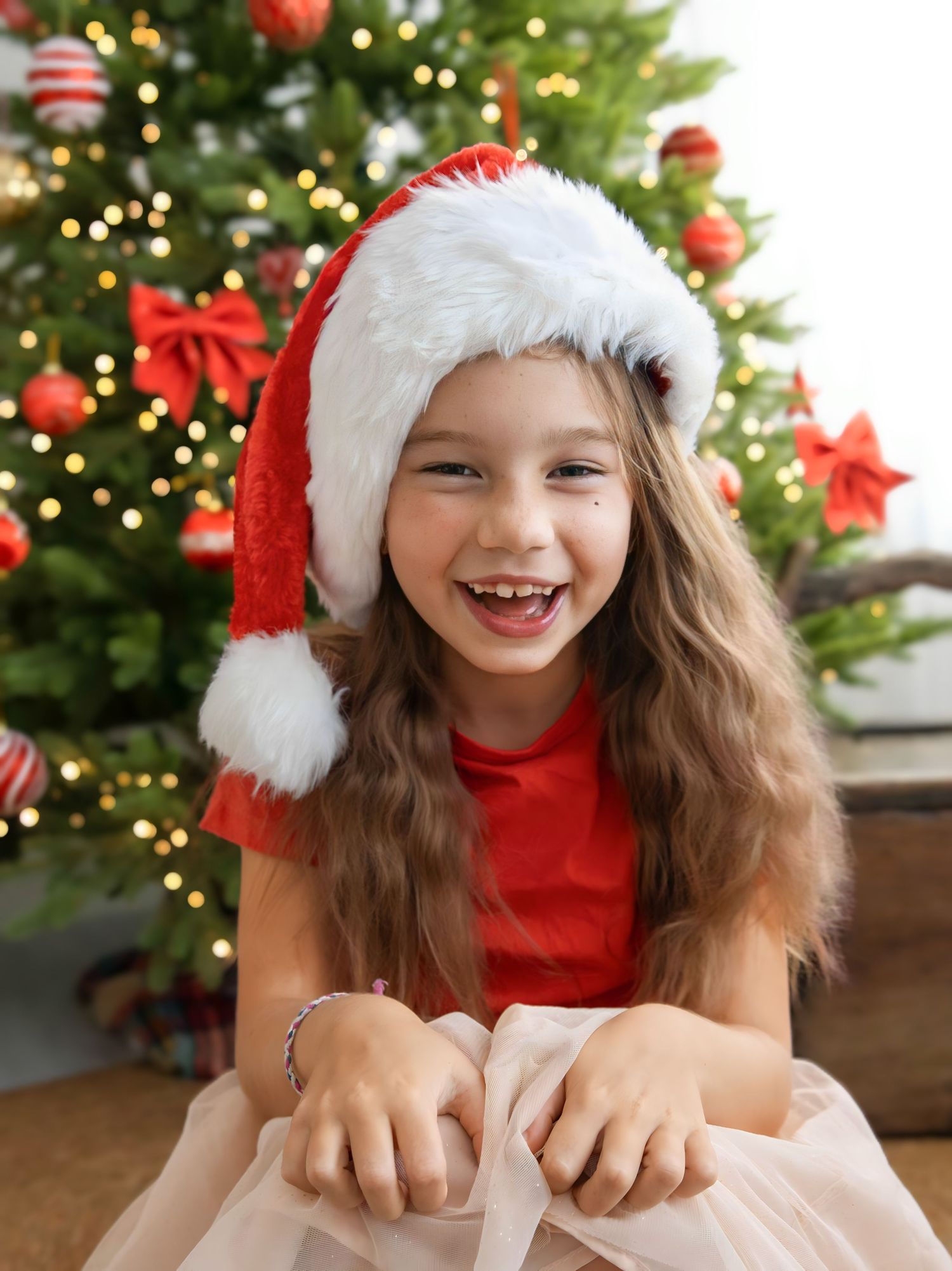 Festive holiday scene with a red Santa hat and Christmas tree decorations in the background.
