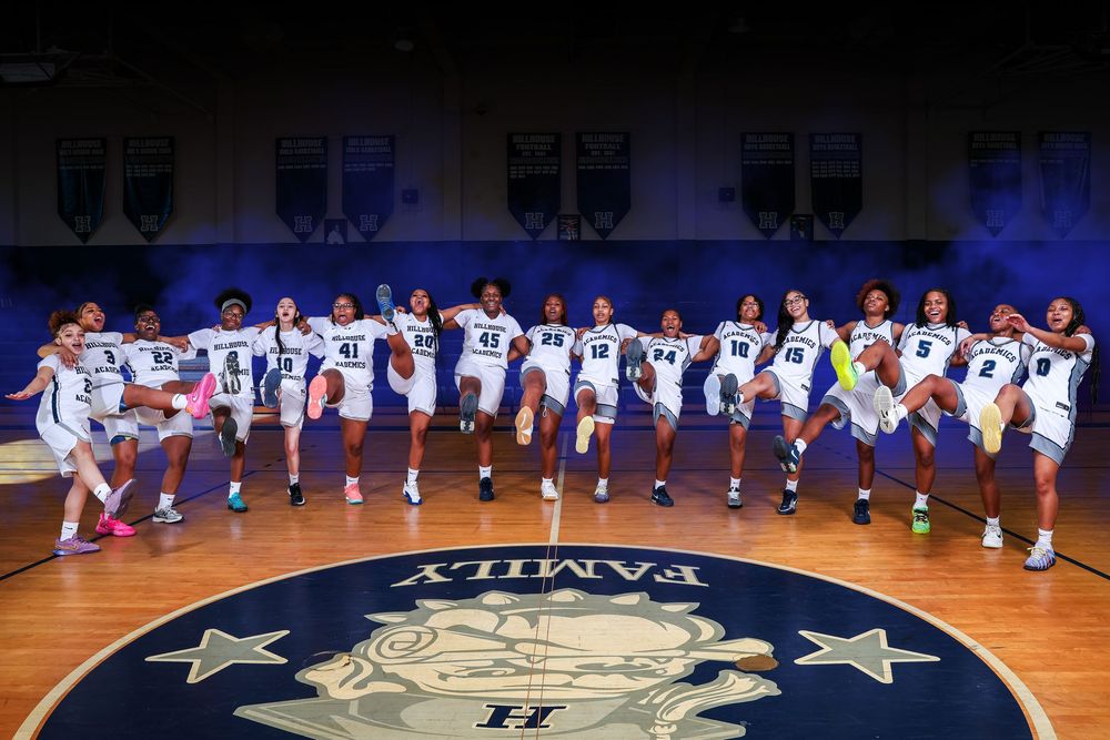 Basketball players line up on the court during a pre-game ceremony with blue lighting effects in an indoor arena.