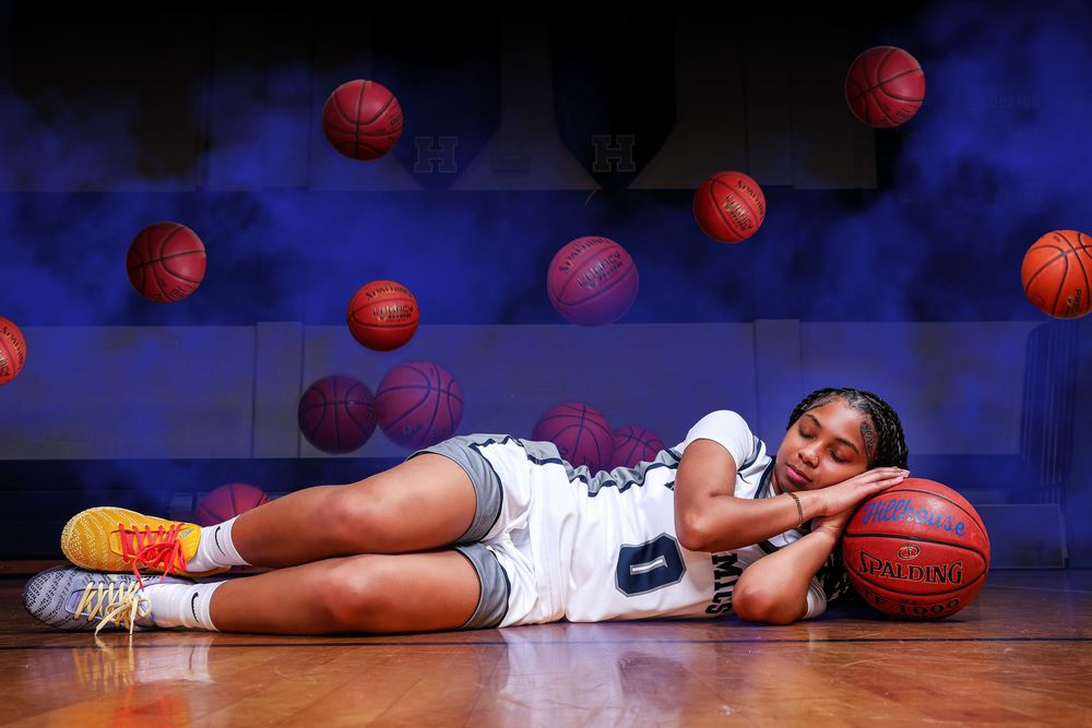 Basketball player lies on court surrounded by scattered orange basketballs in dramatic blue lighting.