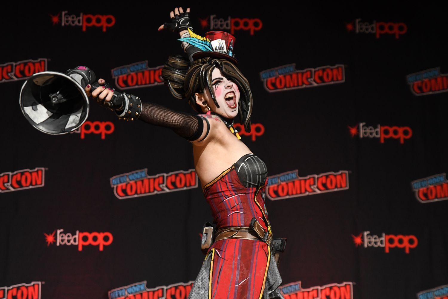 A woman in a vibrant costume stands on stage, holding a microphone, ready to perform for an enthusiastic audience.
