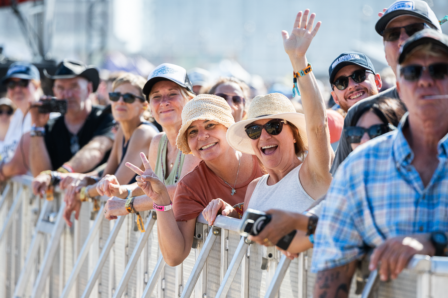 A vibrant crowd of festival-goers enjoying live music, dancing and celebrating under colorful lights and banners.