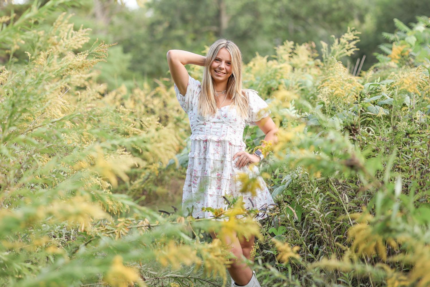 A dreamy portrait in a meadow featuring someone in a flowing white dress among yellow flowers.