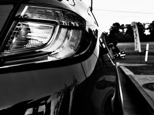 Black and white close-up of a sleek OEM tail light on a polished black car.