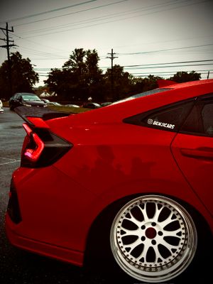Slammed red Honda Civic with smoked tail lights and polished deep-dish wheels.