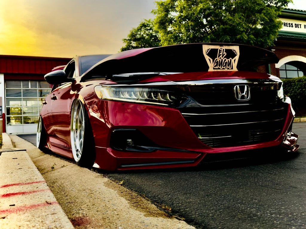 Bagged dark red Honda Accord with custom spoiler parked at sunset.
