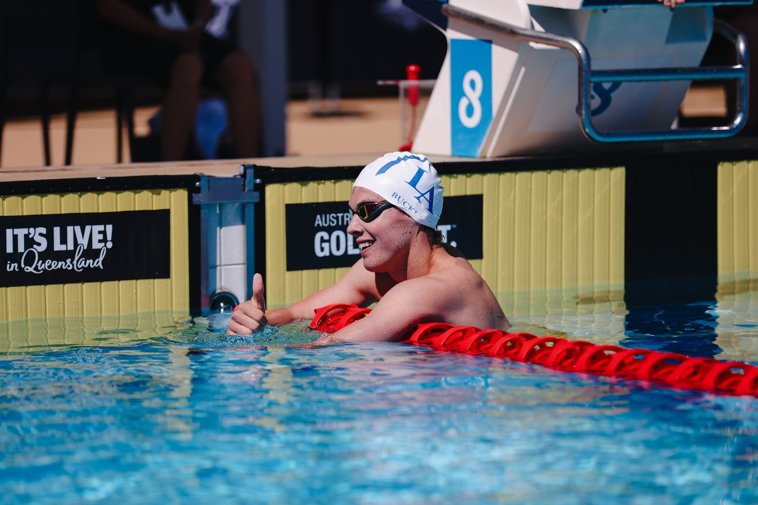 Swimmer rests against lane divider in competition pool with red and white lane markers.