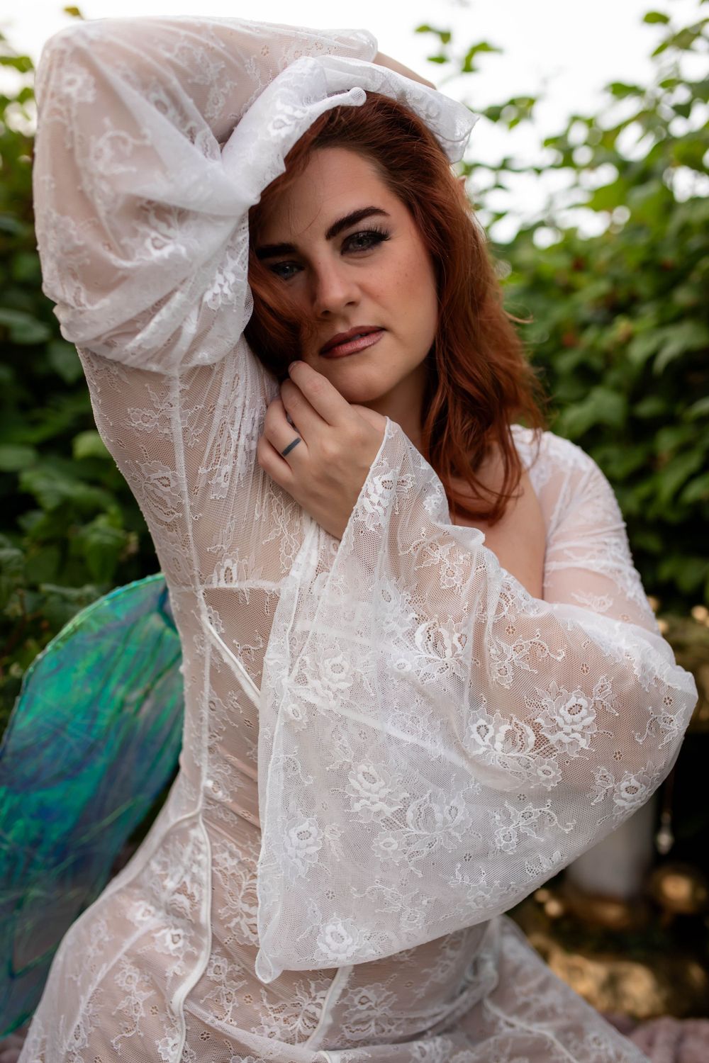 Romantic portrait featuring delicate white lace dress with billowing sleeves in garden setting.