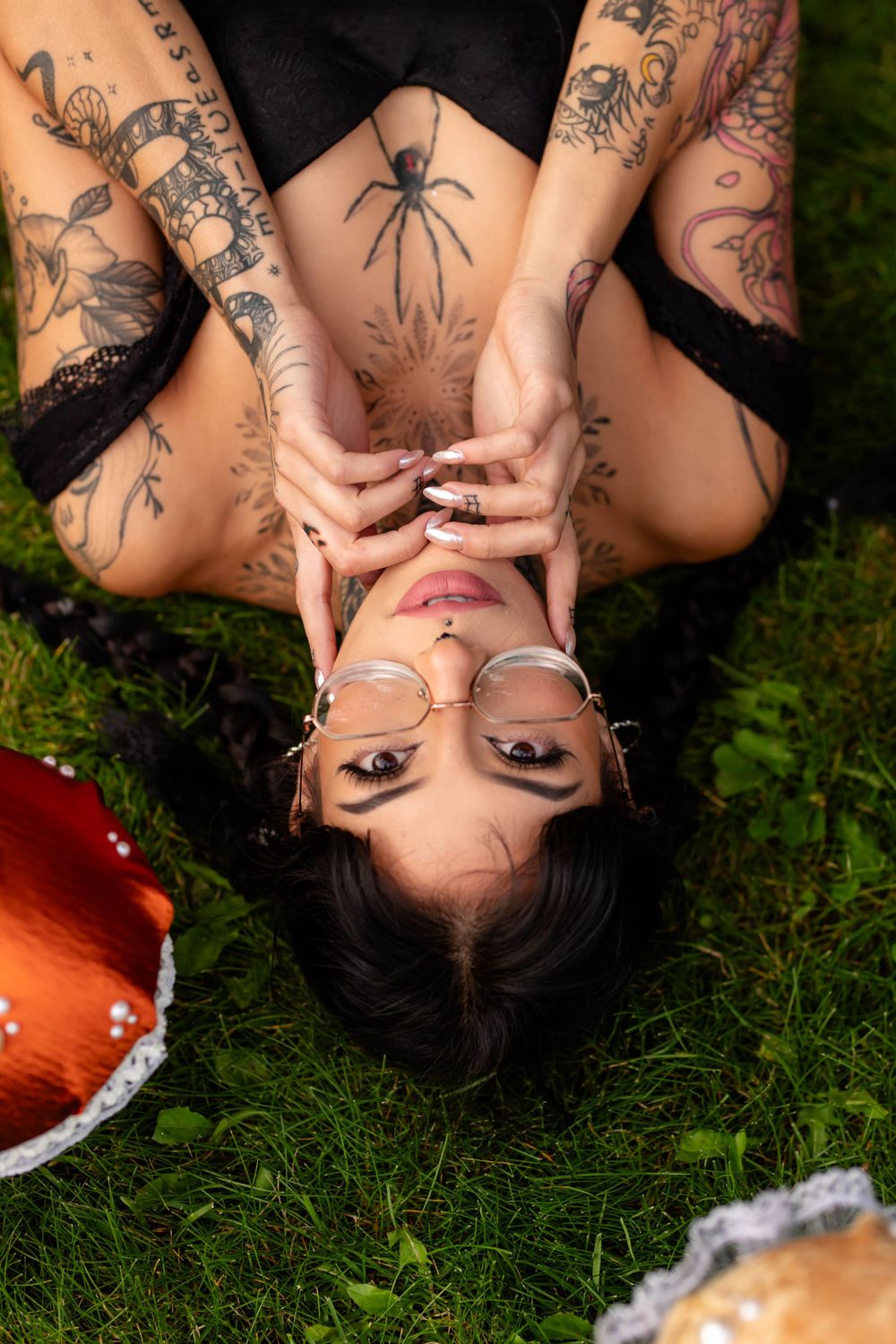 Artistic overhead shot on grass featuring intricate tattoo art and spider design.