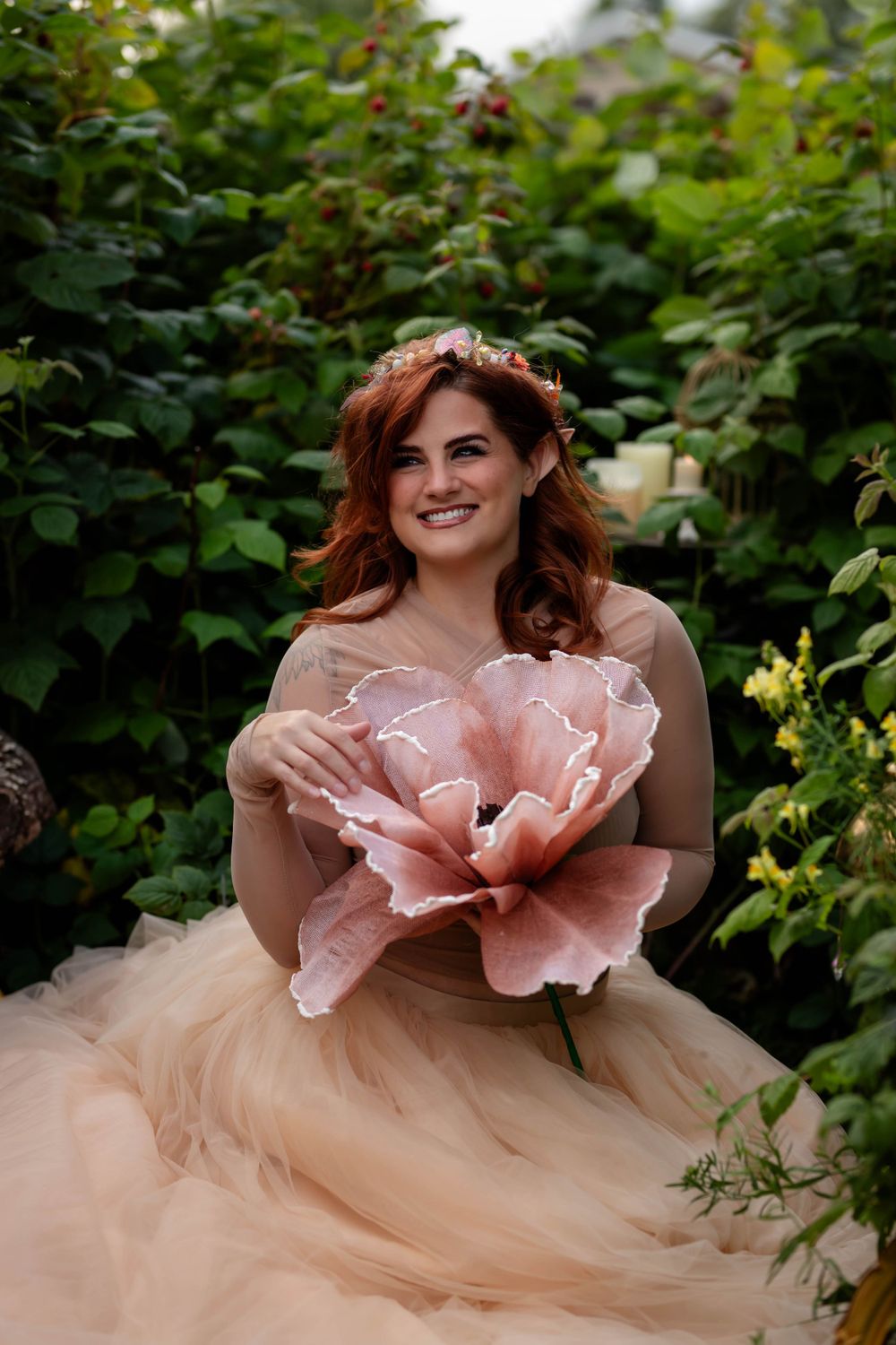 Romantic garden portrait with large pink flower and tulle dress among greenery.