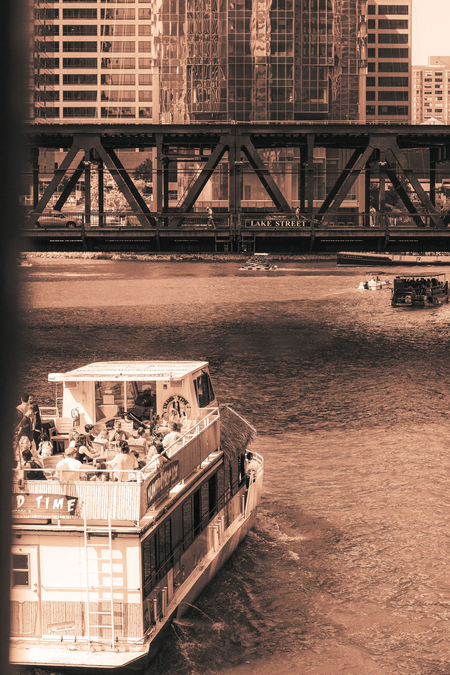 Vintage sepia photograph showing boats docked along a waterfront with urban buildings in the background.