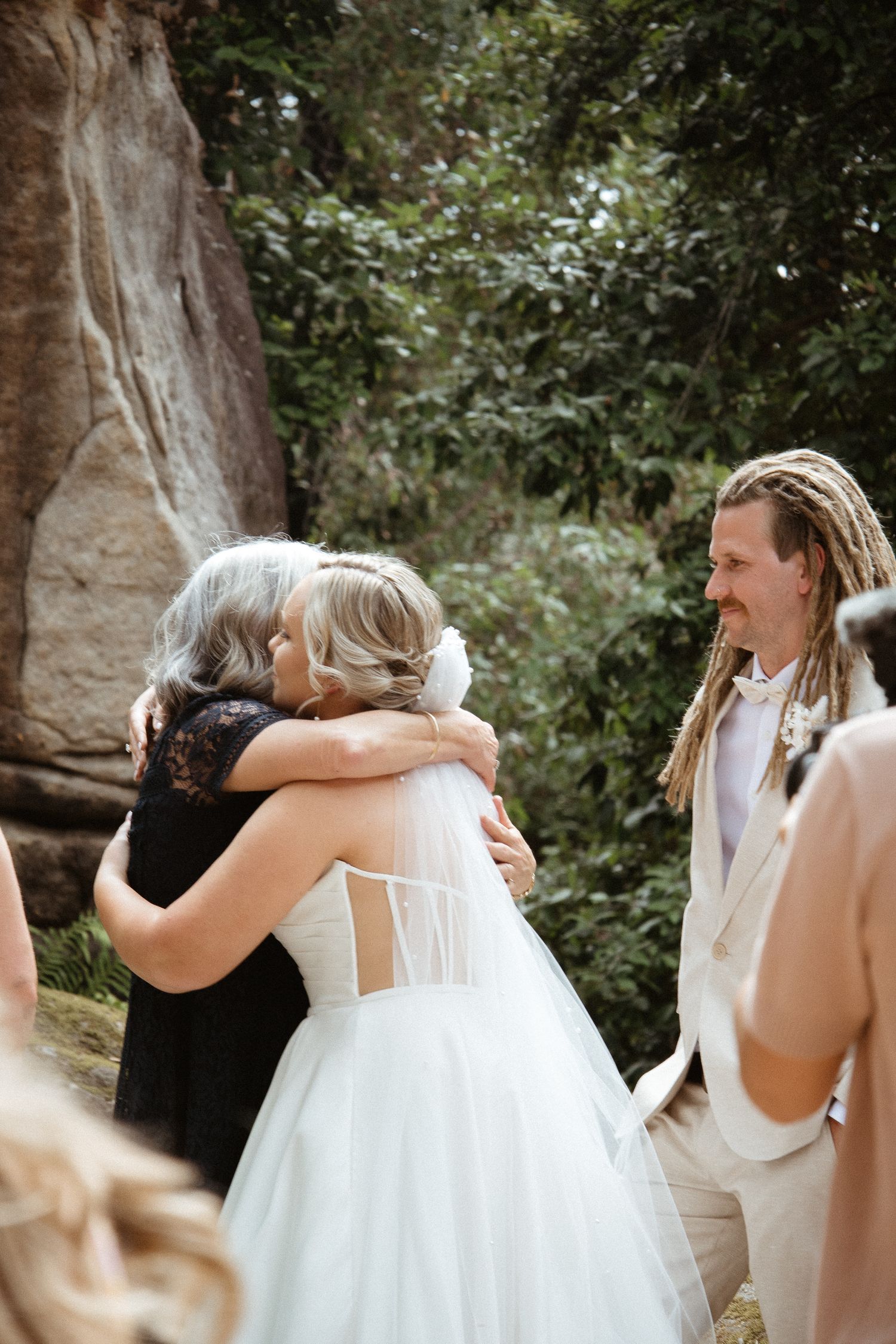 An emotional embrace during a wedding ceremony set against rustic stone walls.