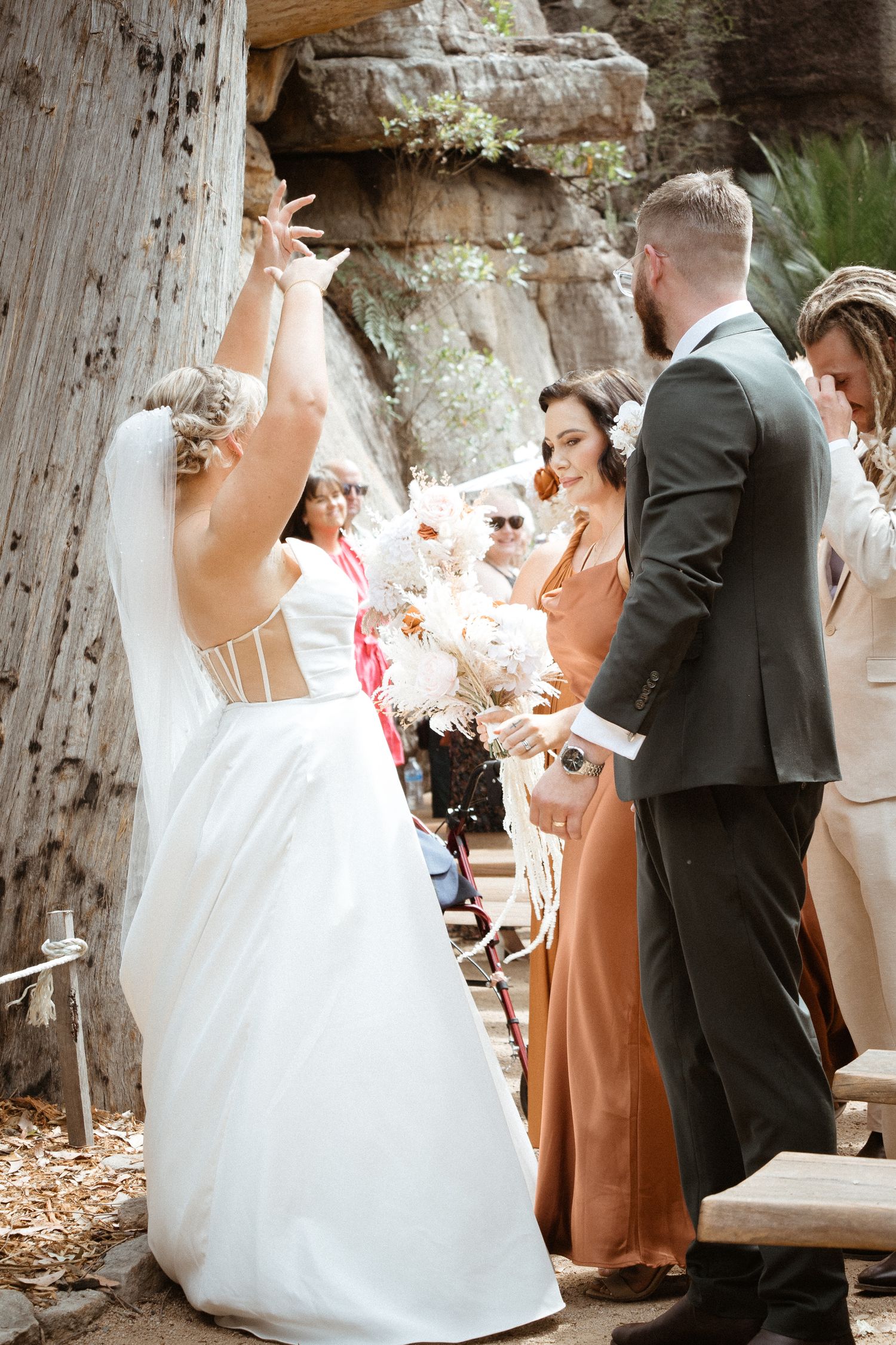 Wedding celebration with guests in formal attire gathered among scenic rock formations.