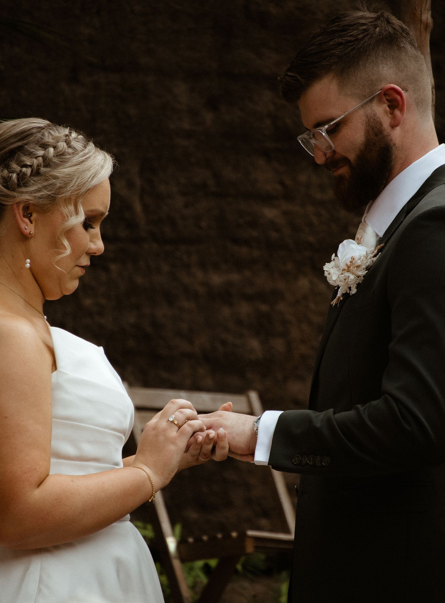 Close-up of wedding ring exchange during outdoor ceremony.