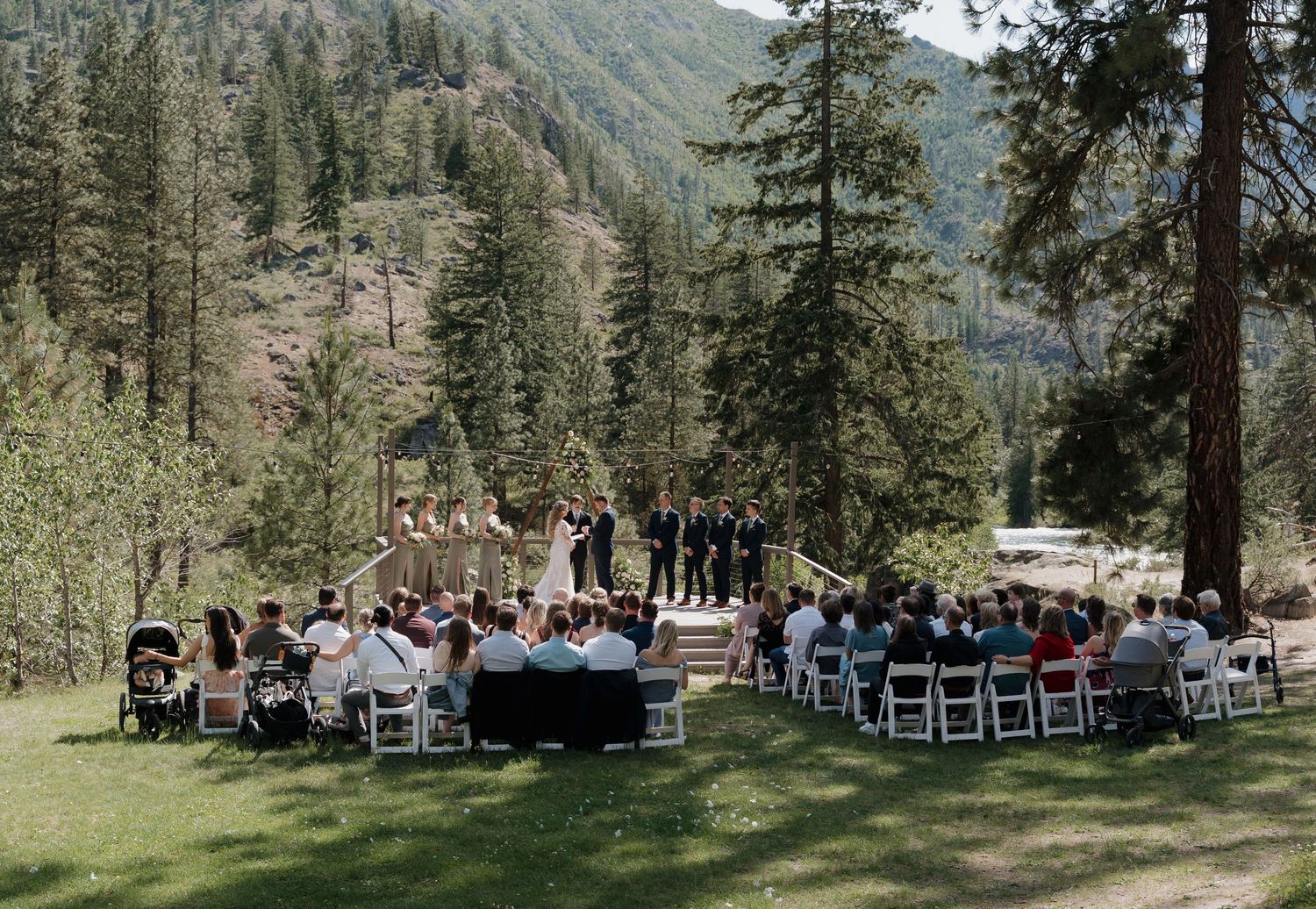 Mountain wedding ceremony setup in a scenic forest clearing with chairs arranged in rows and tall evergreen trees.