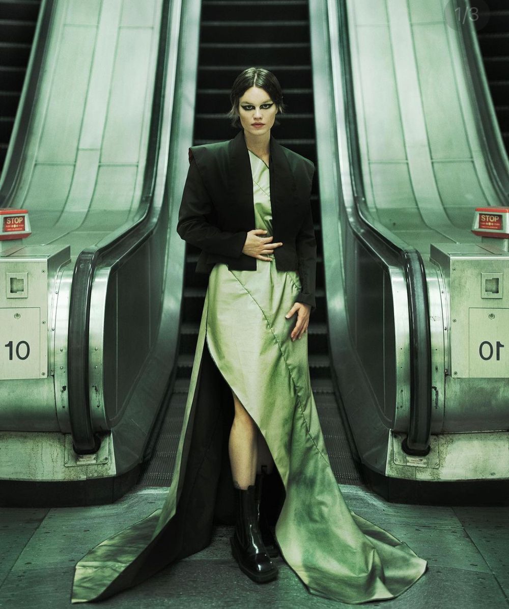 Dramatic fashion photo on escalators featuring long coat and flowing mint green dress.