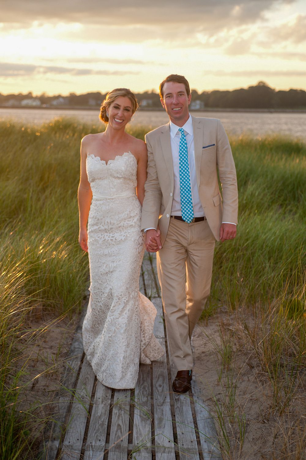 Wedding couple poses on wooden boardwalk at sunset near beach with warm golden lighting | Tom McCall Photography | Eastern Shore MD wedding