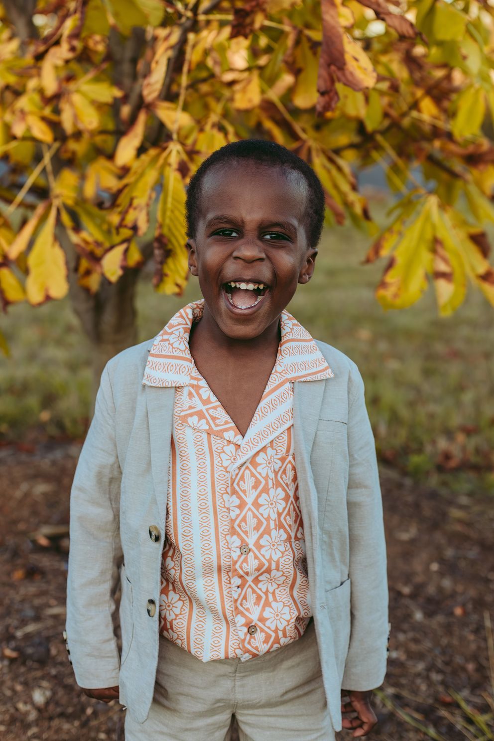 A joyful smile lights up against autumn foliage in Canberra family photography