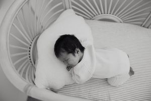 Black and white photo series showing five views of a sleeping baby peacefully resting in a crib.