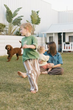 Children sitting together on grass lawn relaxing during a sunny outdoor gathering at a minimalist outdoor space.