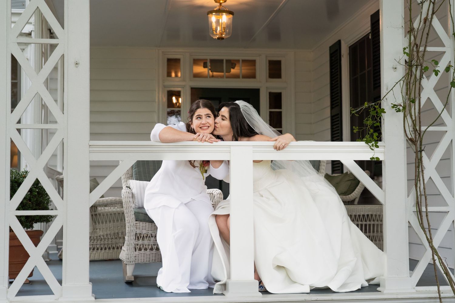 Editorial Image of Lesbian wedding couple kissing being framed by the porch.