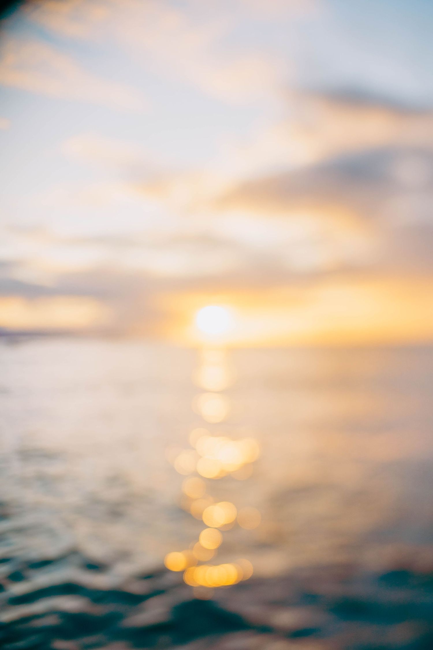 Dreamy ocean sunset with golden light reflecting off rippling waves.