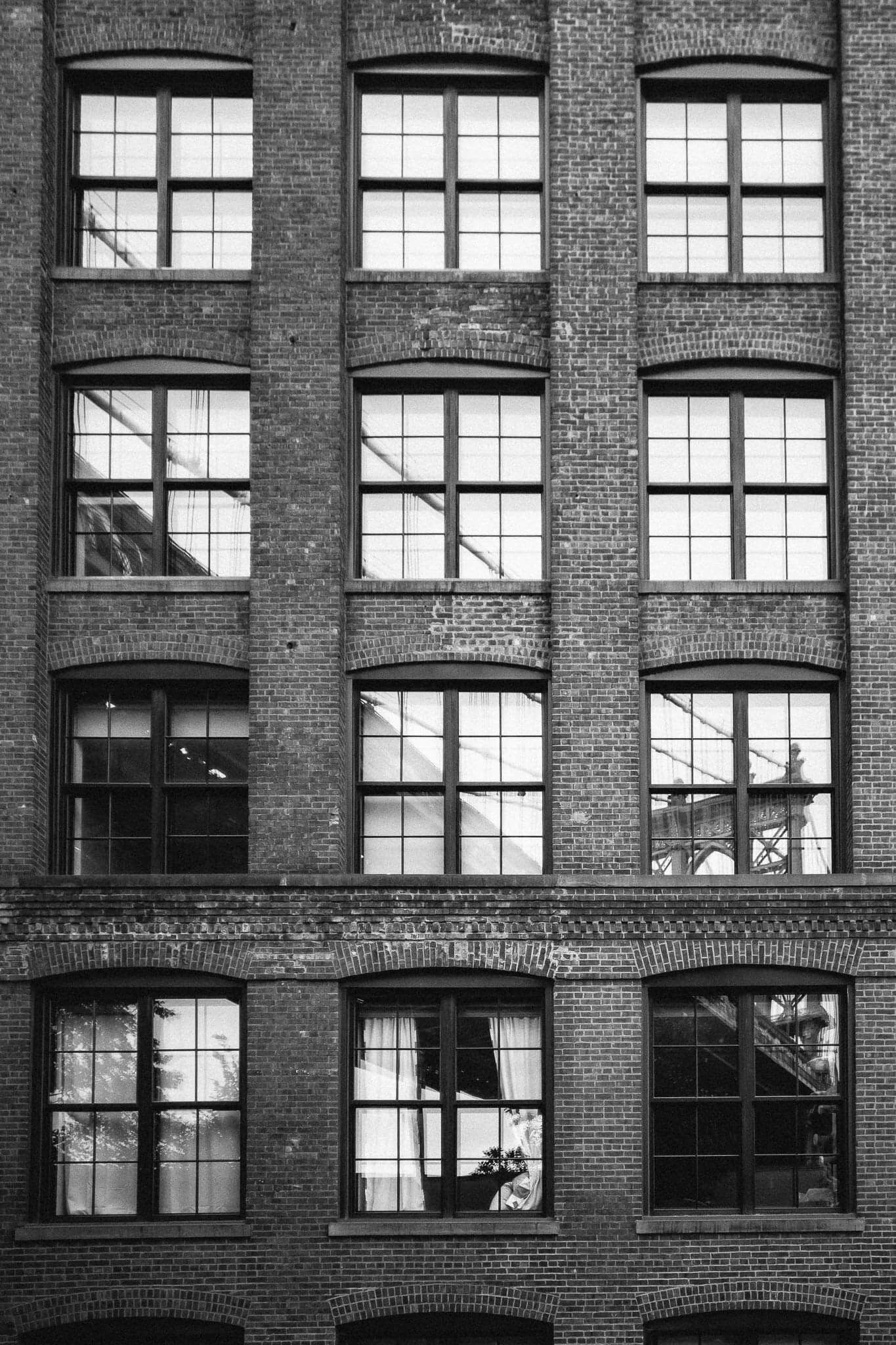 Historic brick building facade with rows of symmetrical windows in black and white.