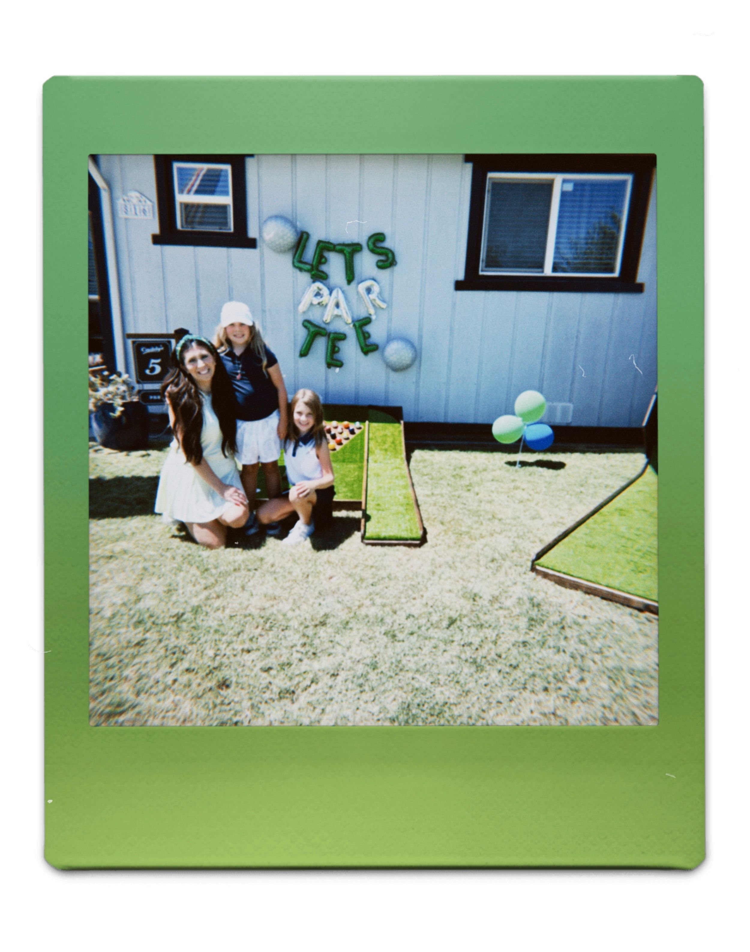 Outdoor party setup with green and blue balloons, miniature golf, decorative bunting, and celebrating in front of a white home in Clovis, CA