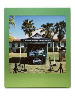 Black promotional banner for Caddy's Mobile Mini Golf setup outdoors for Vintage Day's at Fresno State University in Fresno, CA.