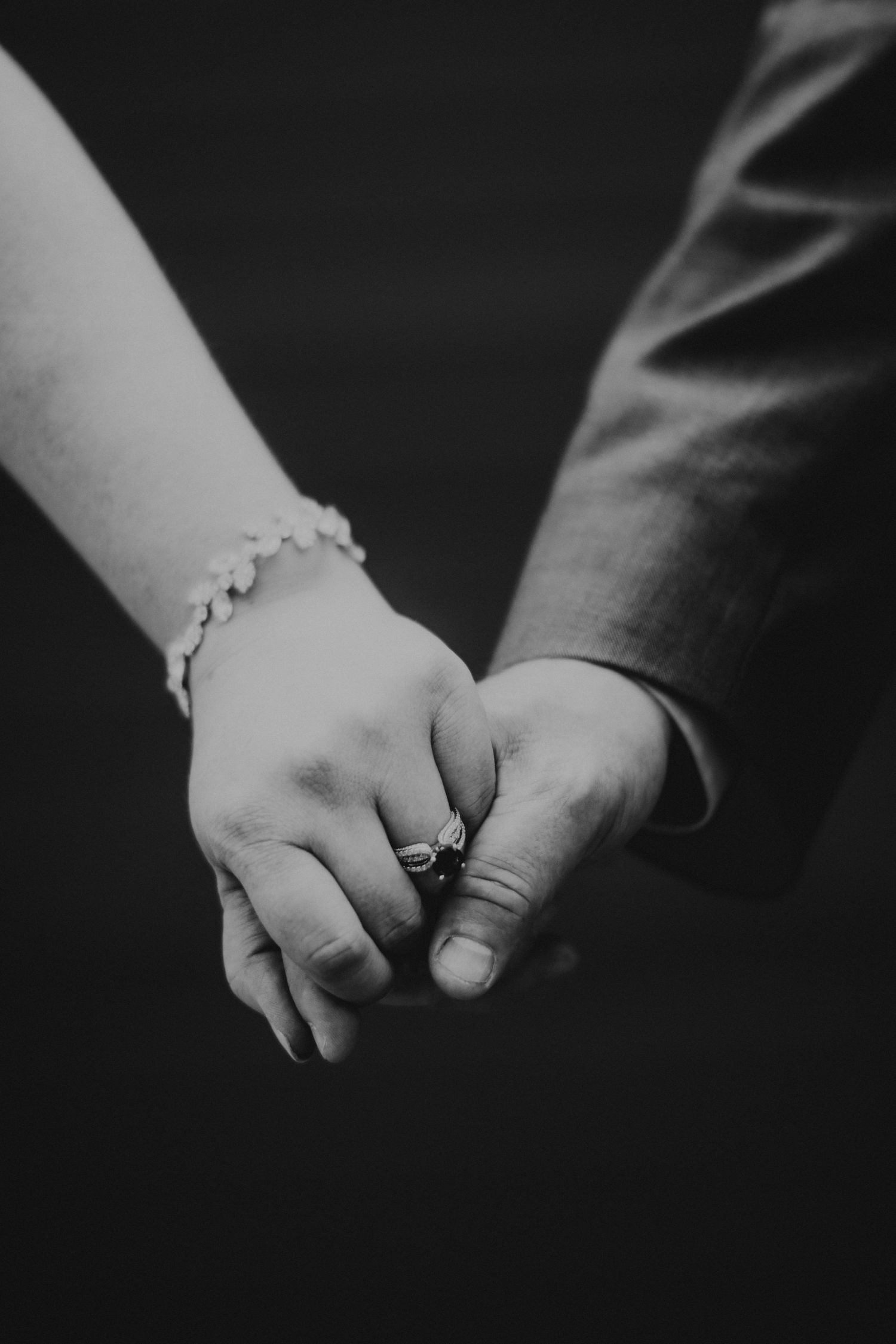 Black and white close-up of hands holding together with engagement rings. Twin Cities wedding photography.