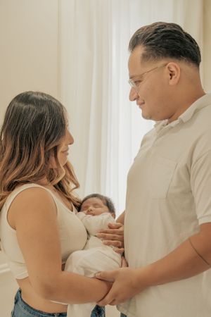 New parents sharing an intimate moment while holding their sleeping baby.