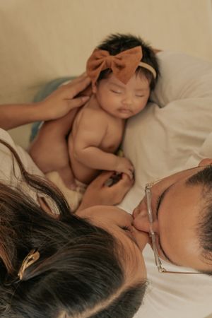 Sleeping baby with bow headband nestled close to parent.