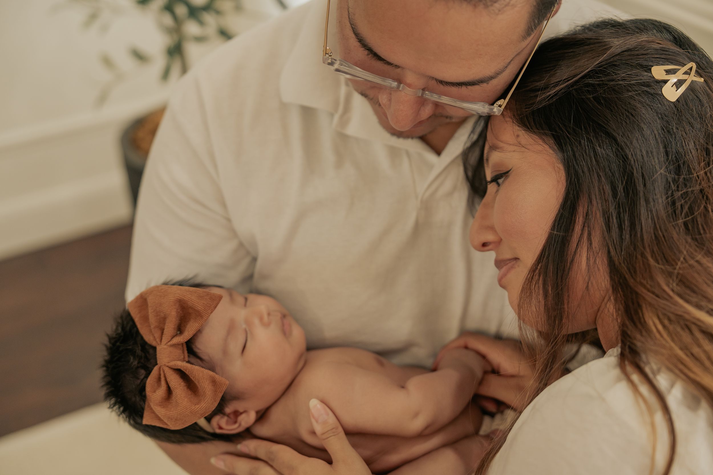 Parents sharing tender moment with sleeping newborn during photo session.