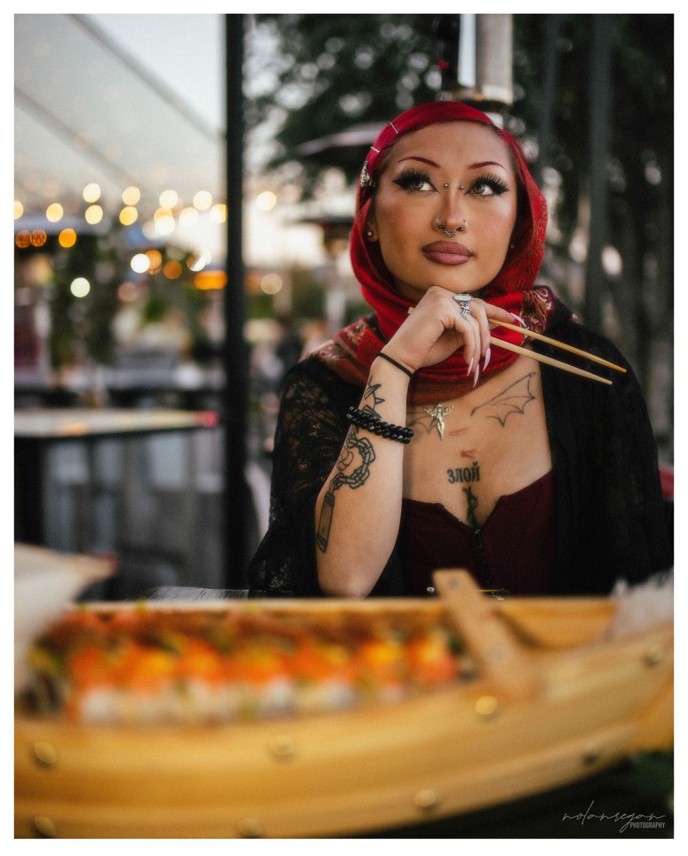 Dining scene at a sushi restaurant with wooden boat plate in the foreground.