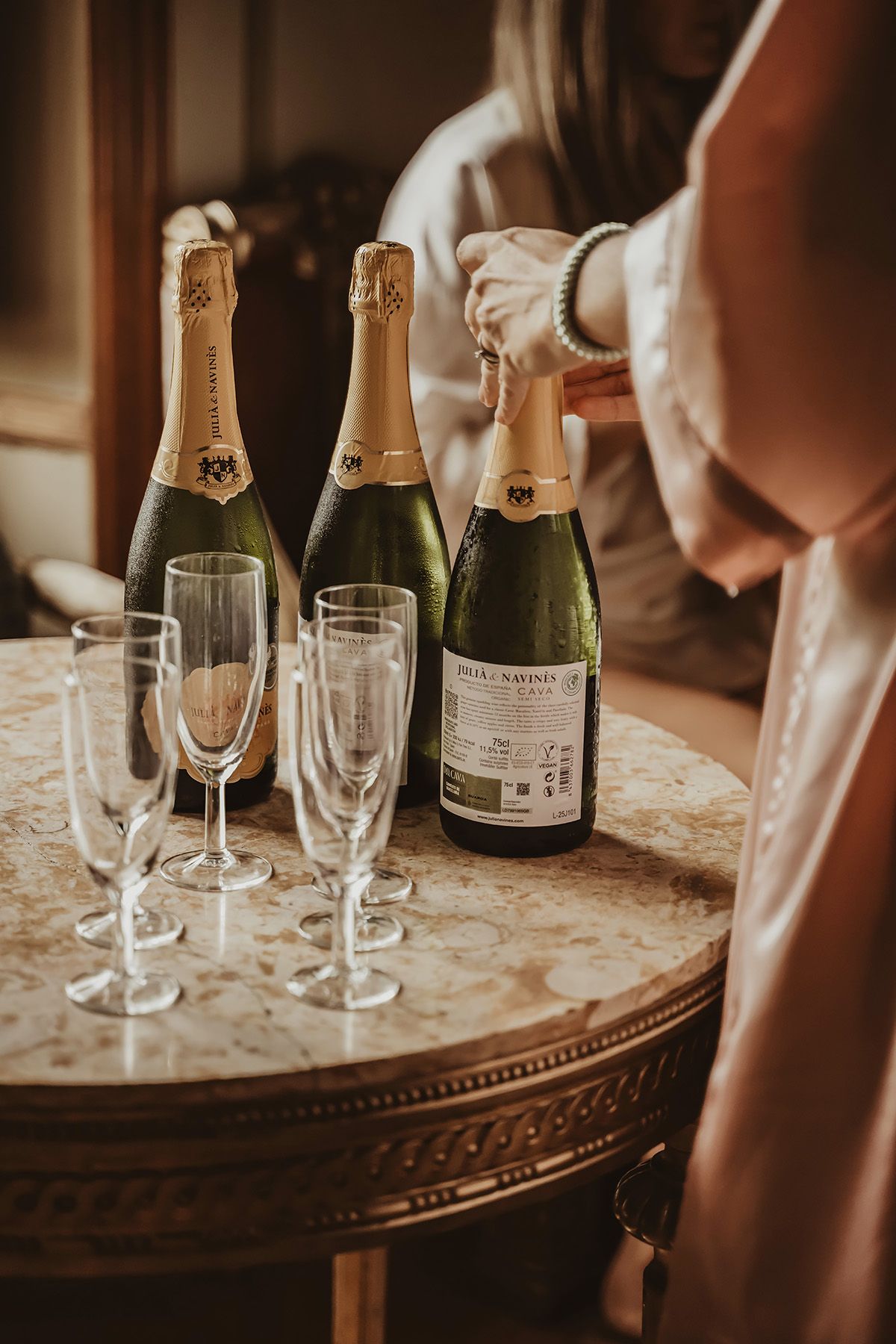Champagneflaskor och glas ståendes på ett vackert antikt bord under förberedelser av bröllop på Rockelstad slott, Södermanland.
