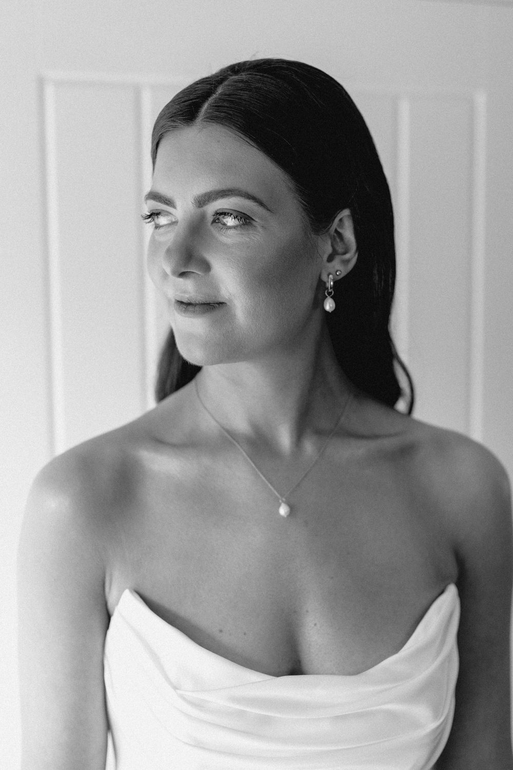 Black and white portrait series showing the same subject in different poses wearing an elegant white off-shoulder top.