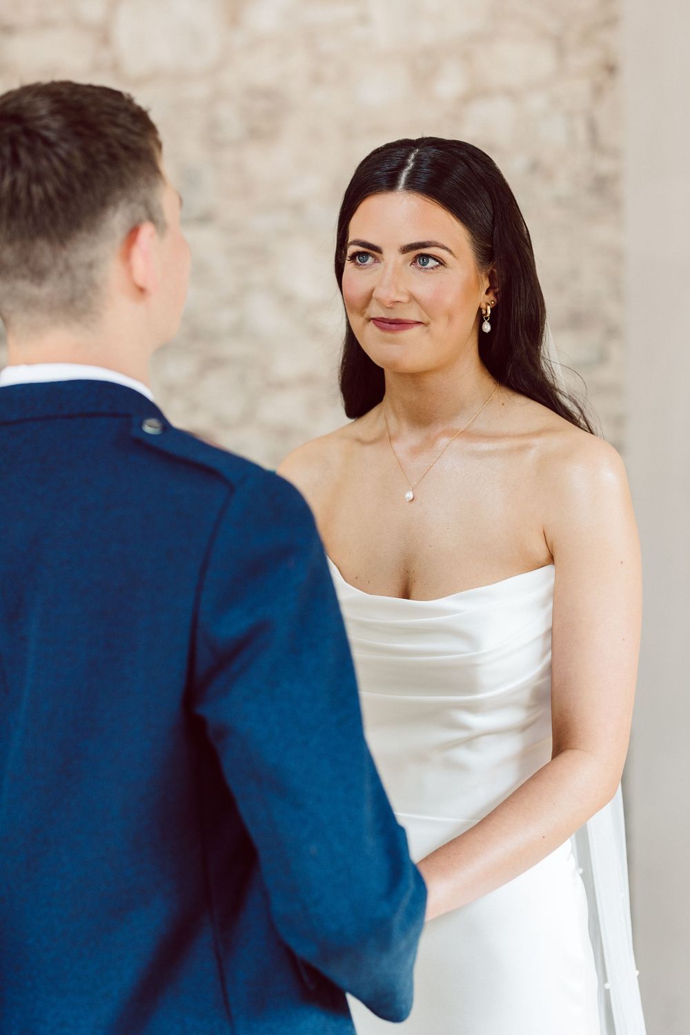 Bride in white strapless gown shares an intimate first look moment with groom in traditional Scottish attire.