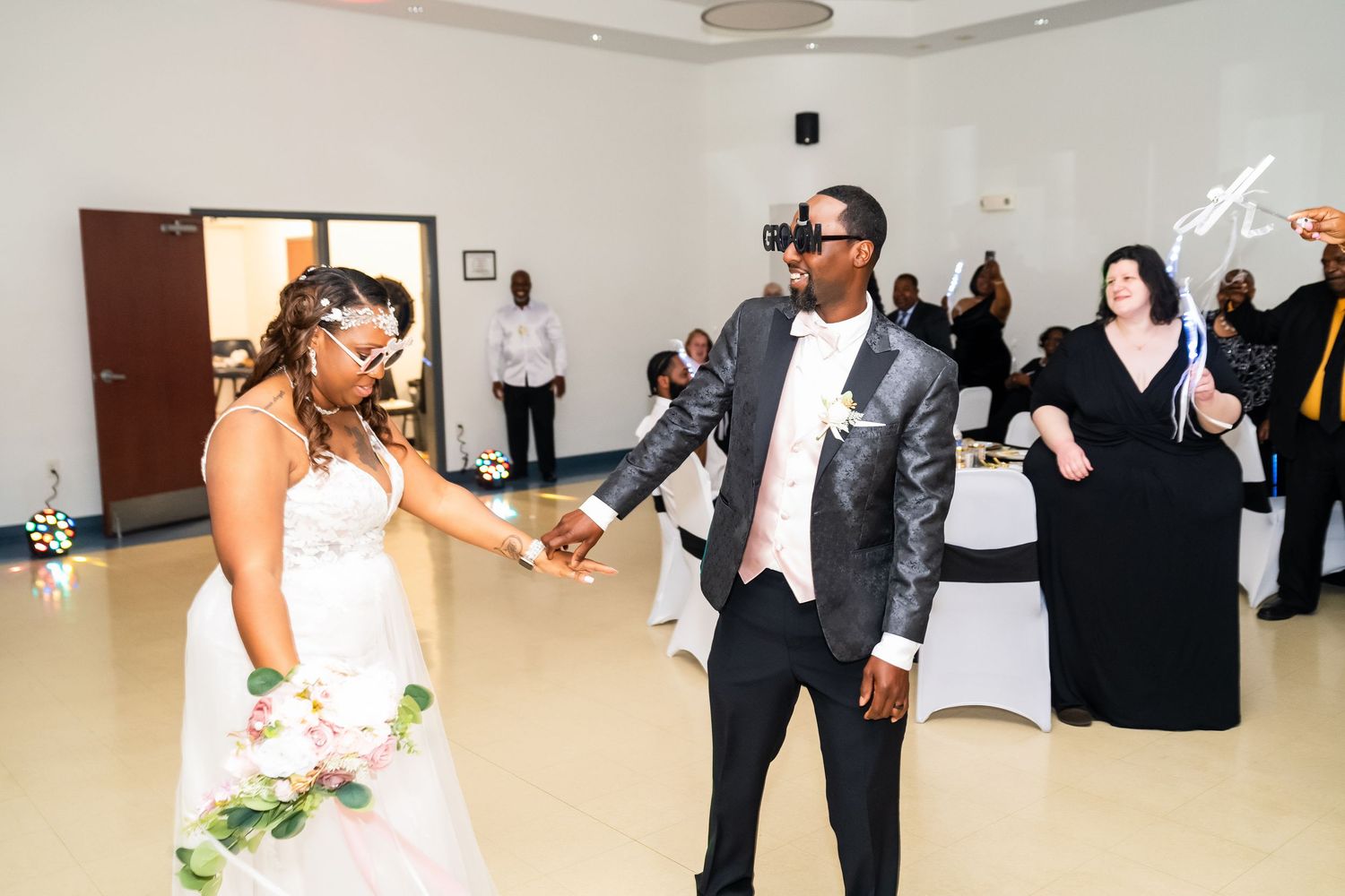 Wedding guests dancing and celebrating together on the dance floor at an indoor reception venue.
