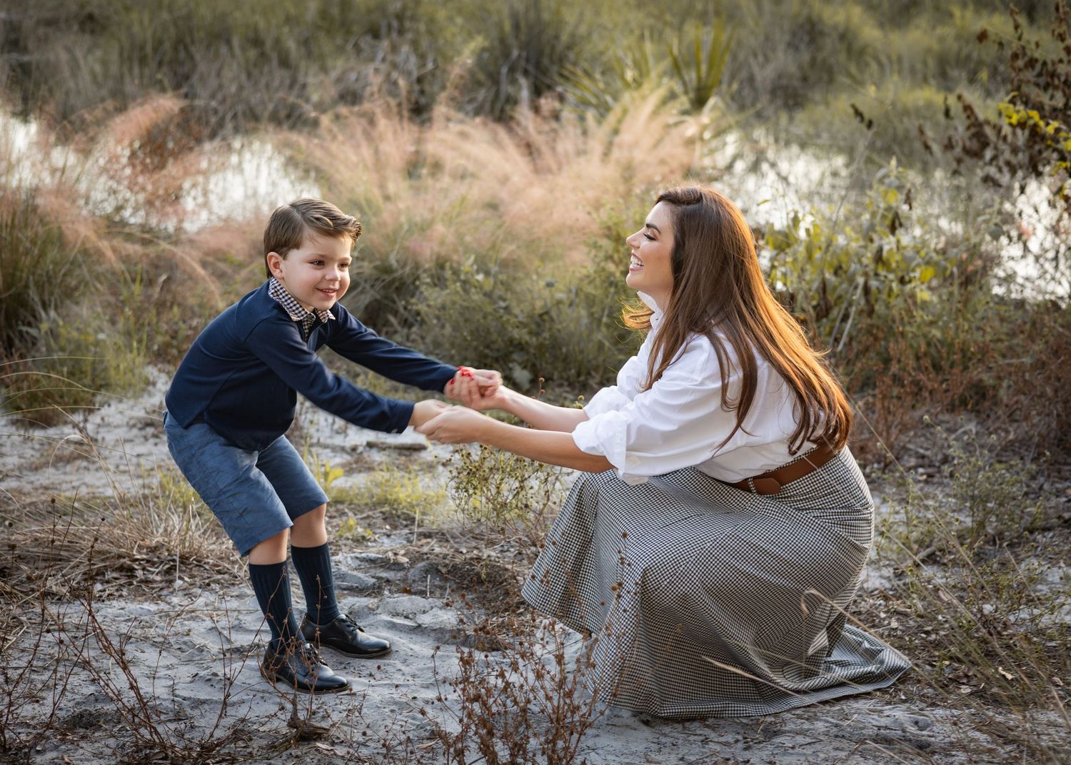 Playful mom having fun with her son spinning and dancing together on an outdoor trail at sunset.