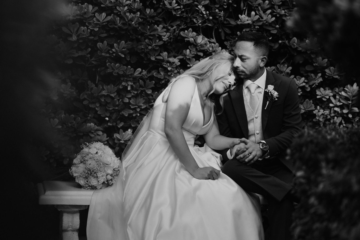 A romantic black and white wedding photo series showing intimate moments between a bride and groom in an outdoor garden setting.